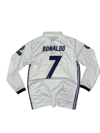 A white long-sleeve soccer jersey laid flat on a beige tiled floor, with navy blue trim, the number 7 on the back, and 'RONALDO' printed vertically. A Champions League patch is visible on the sleeve.